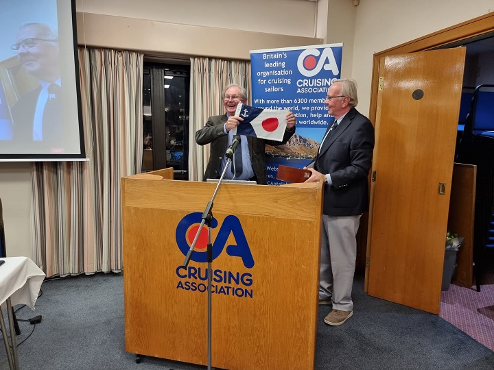 Incoming President, Derek Lumb, presents Jules Dussek with the Past President’s flag